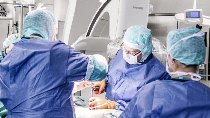 Chirurgen, die auf den Monitor schauen und besprechen, wie mit dem Wirbelsäuleneingriff fortgefahren wird.