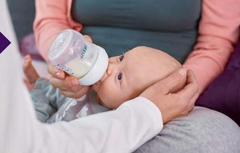 ein Baby, das von einer Frau gefüttert wird