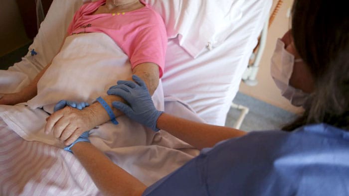 Eine Krankenschwester halt eine altere Patientin an der Hand