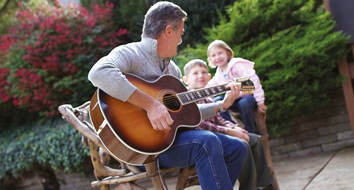 ein Mann, der mit einem Kind und einem Mädchen Gitarre spielt