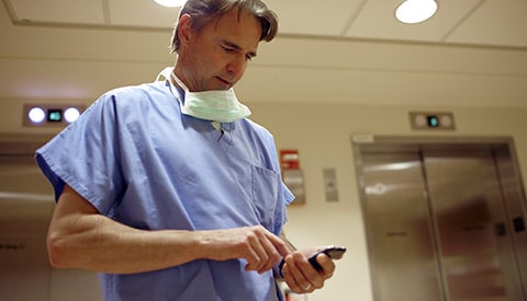 Ein Arzt bei der Durchsicht von Patientenakten auf einem Mobilgerät