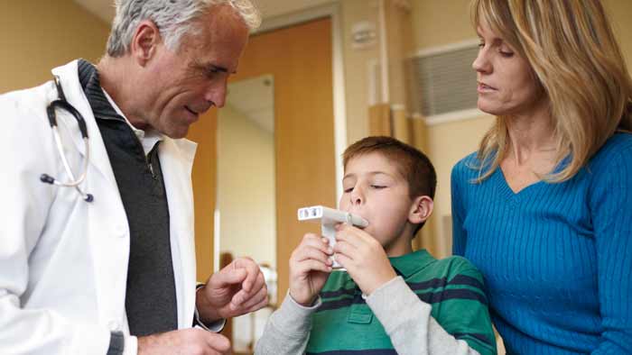 Arzt, der Kind mit Asthmaprodukt hilft