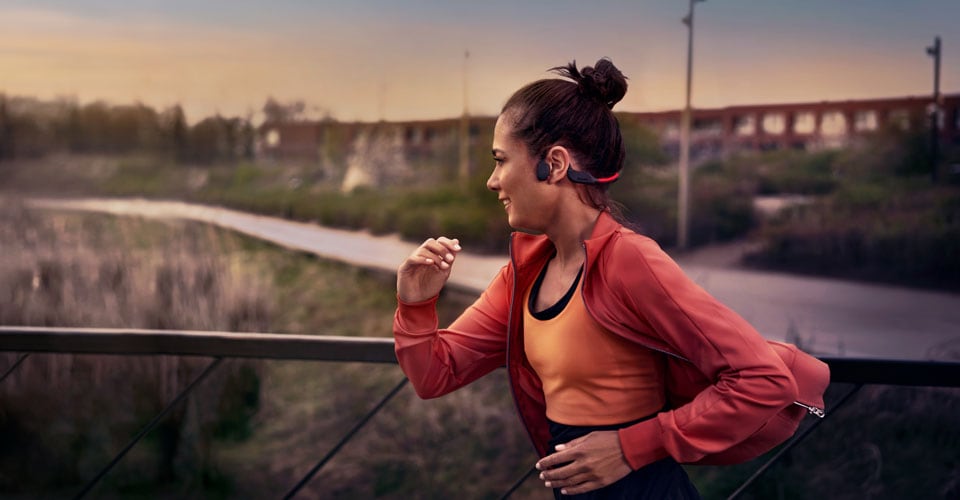Athletin, die beim Laufen im Freien Kopfhörer mit Knochenschall-Übertragung trägt