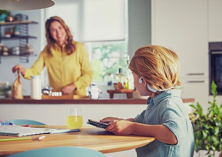 Junge, der sich ein Video anschaut und dafür Philips kabellose Open-Ear-Kopfhörer für Kinder verwendet.