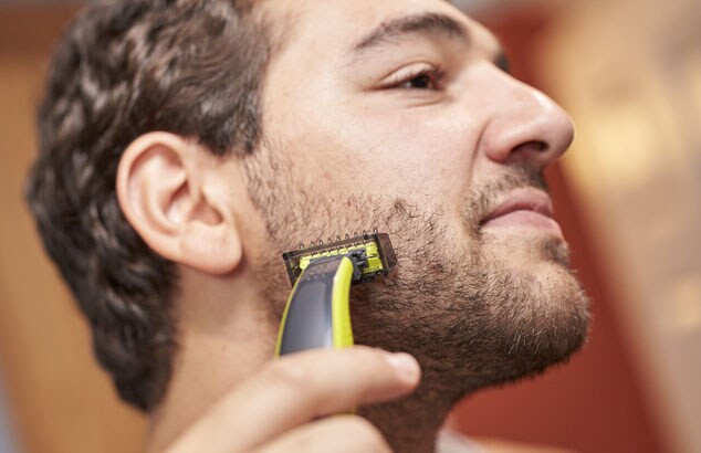 Mann,   der den Bart an der Wange mit Philips OneBlade trimmt.