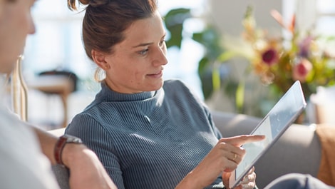 Frau auf Sofa schaut auf Tablet App