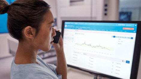 Mitarbeiterin im Gesundheitswesen vor dem Bildschirm am Telefon